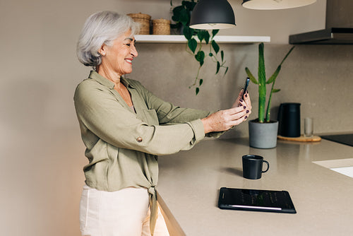 Grey-haired senior woman taking a video call at home
