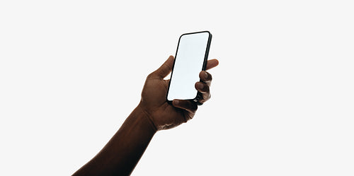 Hand holding a smartphone with a blank white screen on a plain background