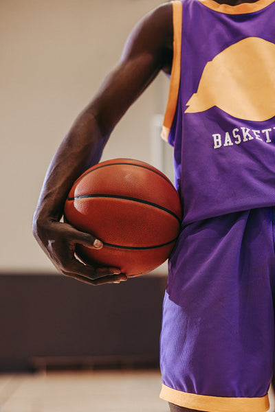 Close up of basketball player holding the ball during a game in purple and gold uniform