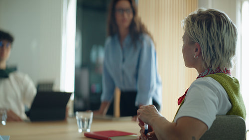 Woman receives applause from coworkers during a business meeting in the office