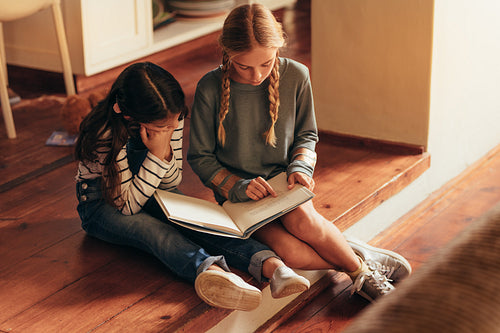 Girl reading storybook for her little sister