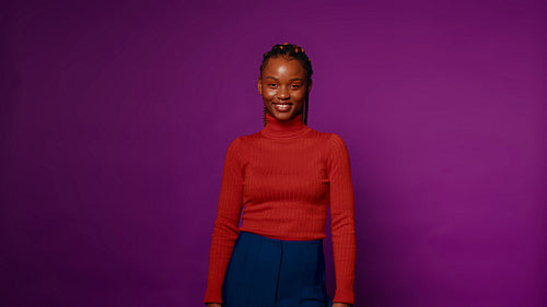 Young woman laughs heartily on purple studio background