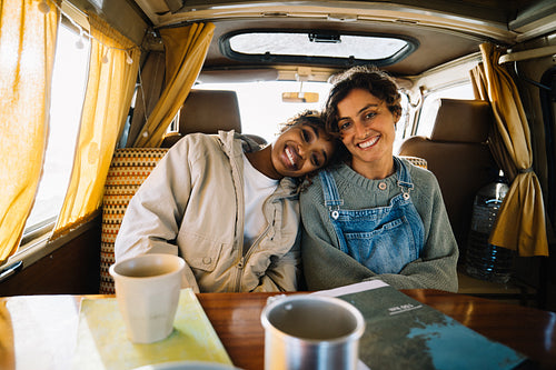 Friends embrace inside cozy van during road trip escape