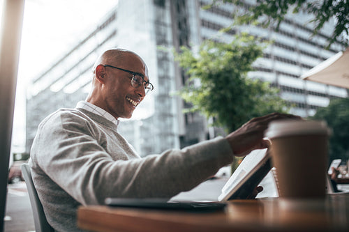 Businessman sitting at a restaurant reading book.
