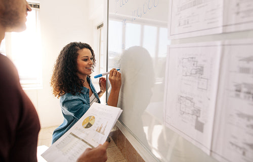 Woman entrepreneur writing on whiteboard in office