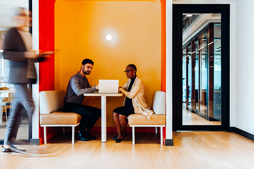 Two professionals discussing ideas inside a bright and colorful office area