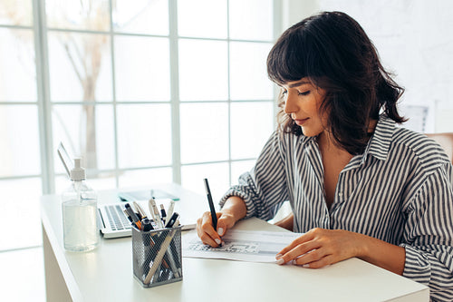 Architect sitting at her desk and drawing plans