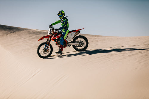 Motocross rider on top of the sand dune