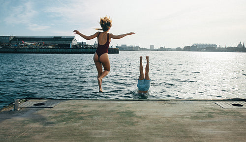 A playful jump captures swimming friends above the water beside the dock.
