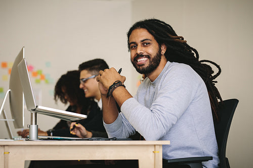 Smiling businessman working in office sitting at his desk