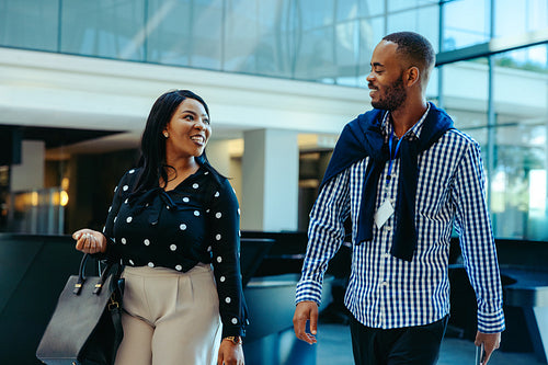 Professional colleagues walking and engaging in conversation in a corporate office lobby