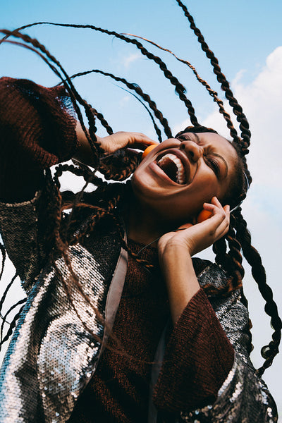 Black woman laughs while listening to music outdoors