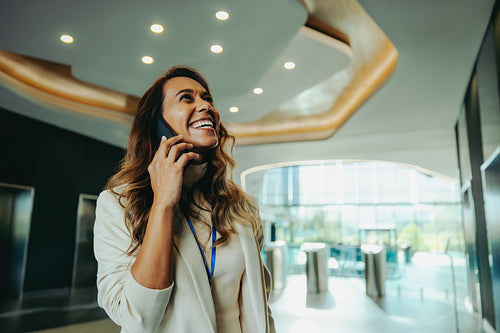 Indian businesswoman talking on phone in modern office lobby