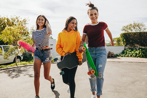 Girls walking in the street holding skateboards