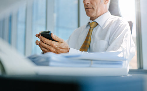 Senior business man using mobile phone in office
