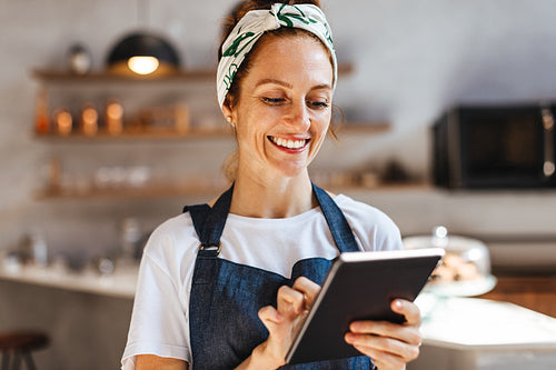 Happy young woman using a touchscreen tablet to manage her coffee shop