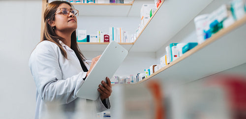 Female pharmacist stocktaking in a chemist