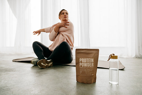 Protein powder highlighting wellness with woman stretching post workout