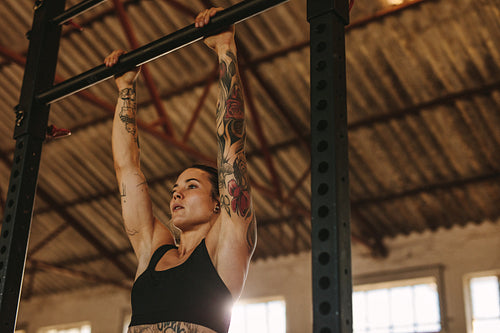 Woman doing pull up workout in fitness studio