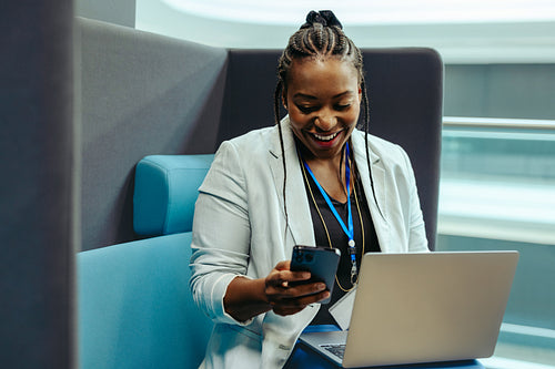 Corporate professional smiling while working on laptop and phone