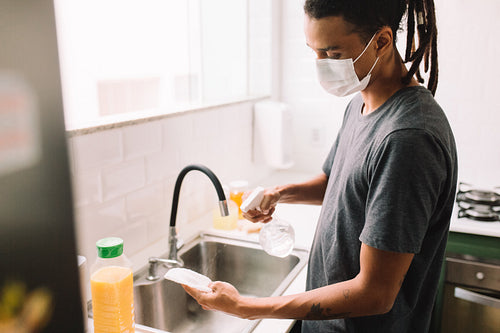 Young man disinfecting groceries during the coronavirus pandemic