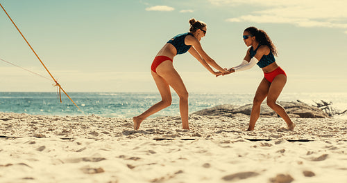Victorious women's volleyball team celebrating championship win on a sunny beach