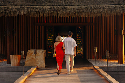 Couple entering luxury resort dining area during sunset for a romantic dinner
