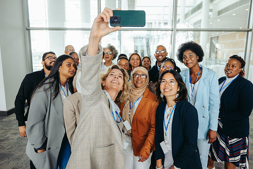 Diverse business team taking a group selfie together at a company event