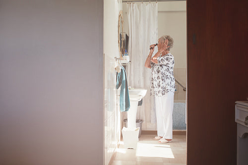 Elderly woman getting ready in bathroom