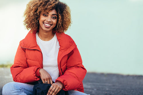 Smiling woman sitting outdoors holding a bag