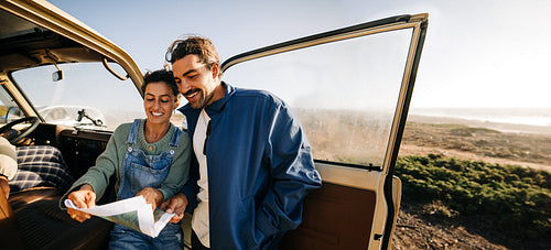 Choosing the way forward: Couple study their map by the van door