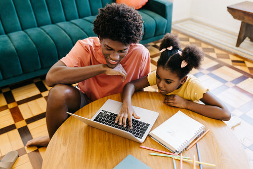 Brother helping his sister do her homework with online learning material