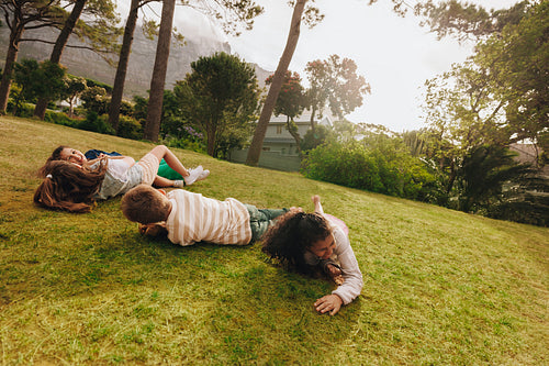 Children playing and laughing on a grassy hillside in a park setting