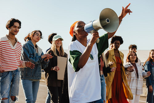 Group of diverse young adults protesting outdoors with a megaphone