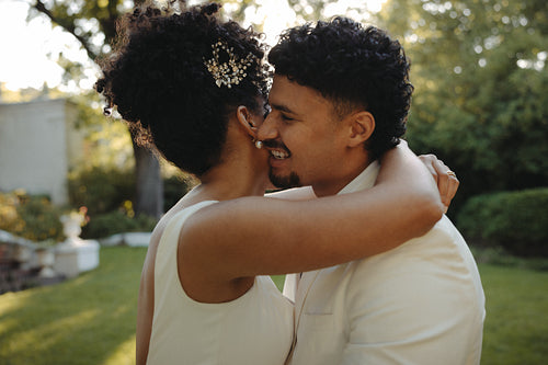 Bride and groom embracing lovingly outdoors on their wedding day