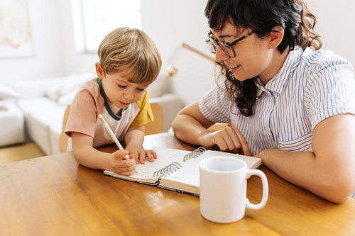 Boy learning how to write with mom