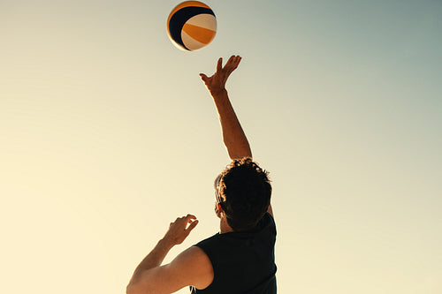 Pro volleyball player soaring in mid air during championship game at coastal beach