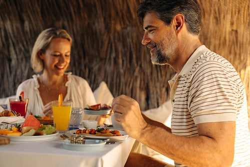 Smiling couple enjoying breakfast at hotel with delicious food and drinks