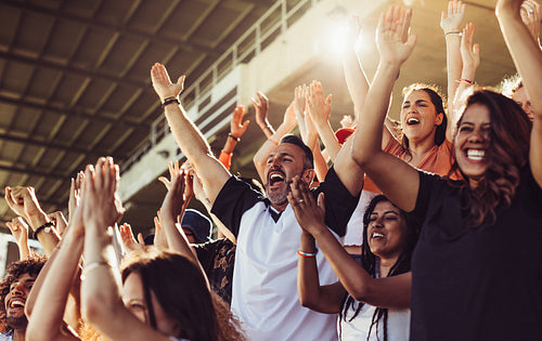 Crowd of sports fans cheering during a match in stadium