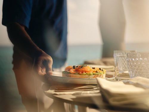 Waiter serving in villa breakfast at the table at overwater villa