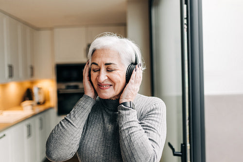 Elderly woman enjoying some music on wireless headphones
