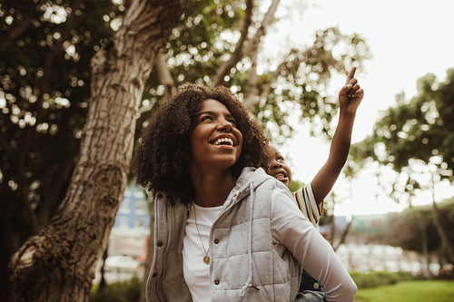 Woman giving son a piggyback ride at park
