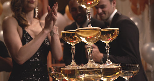 Pyramid of champagne glasses with people dancing