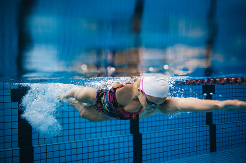 Female swimmer in action inside swimming pool.