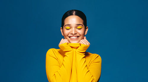 Feeling gorgeous in makeup, young woman smiles and celebrates her beauty in a studio