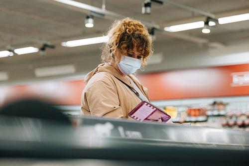 Woman with face mask shopping grocery at store