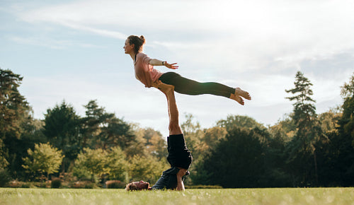 Fit young couple doing acro yoga on park