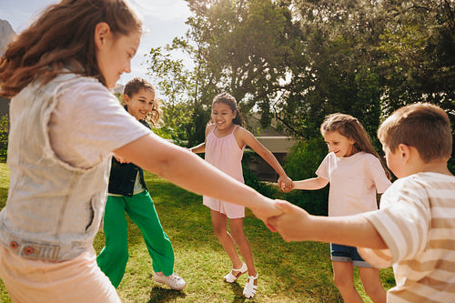 Children holding hands and playing joyfully in a green outdoor park