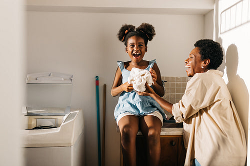 Young daughter helping her mom out with laundry washing at home