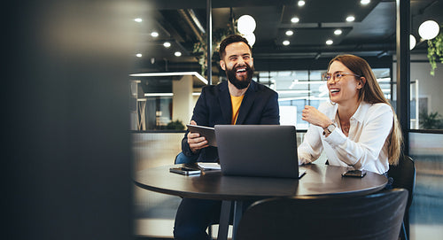 Two happy young businesspeople working together 